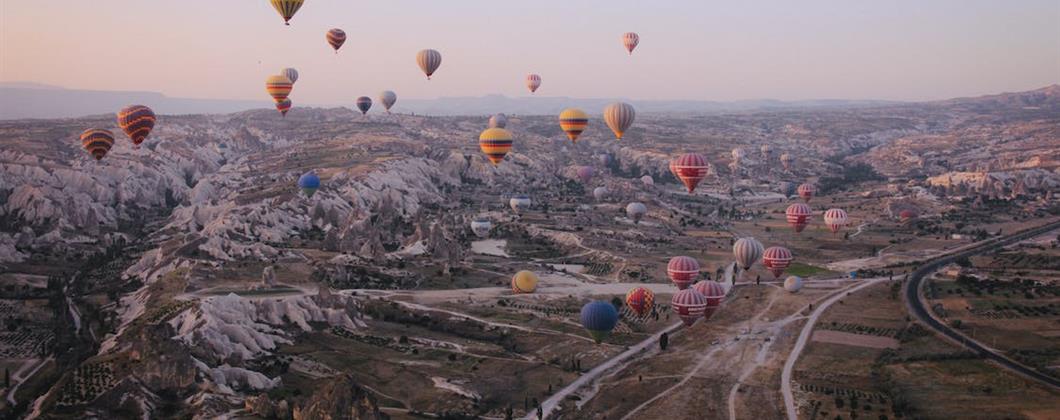 hot air balloons flying over arid landscape at dusk