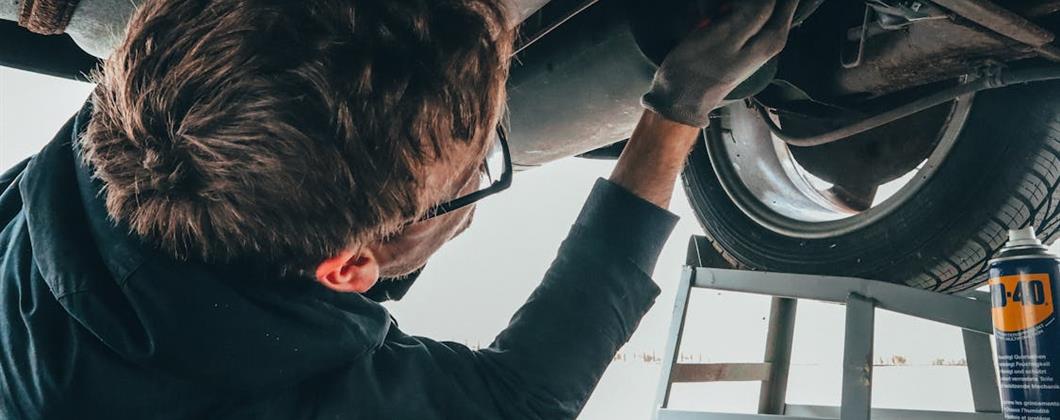 Motor trade employee working on the underside of a vehicle